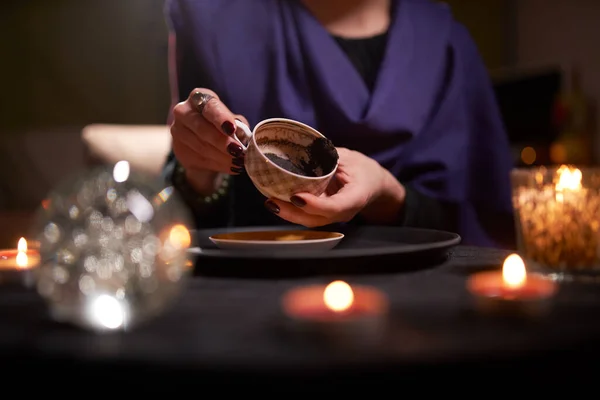 Primer plano de las mujeres adivinadoras manos adivinando en los terrenos del café en la mesa con la bola predictiva — Foto de Stock