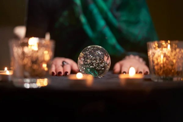 Mujer adivina adivinando en bola mágica en la mesa con velas encendidas — Foto de Stock