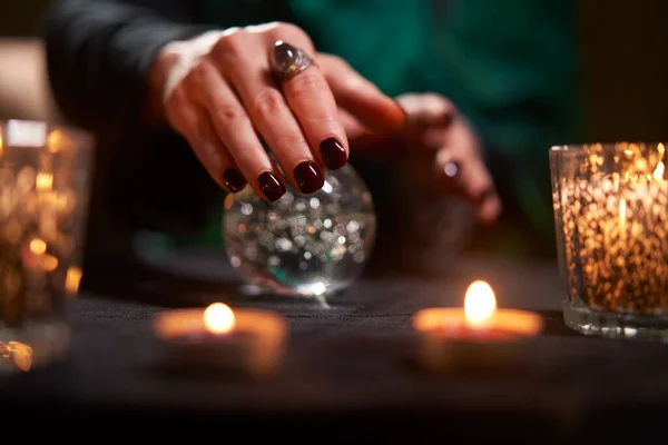 Gros plan de diseur de bonne aventure divinant sur une boule magique à table avec des bougies allumées — Photo