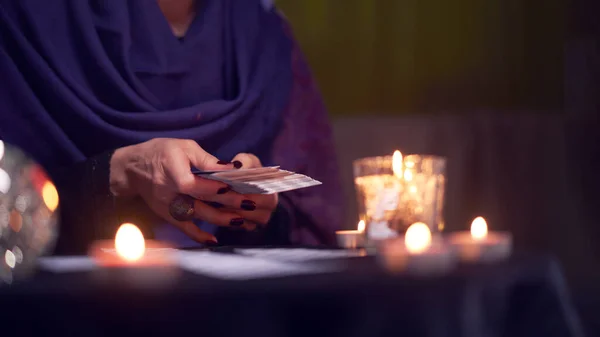 Close-up of soothsayer woman guessing on cards sitting at table with burning candles, magic ball — Stock Photo, Image