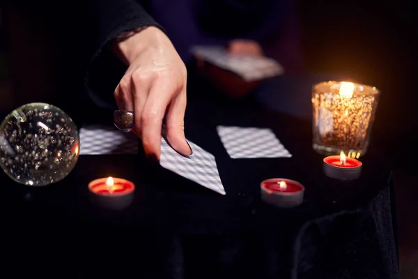 Fortuneteller gudomar på kort som sitter vid bordet med ljus — Stockfoto