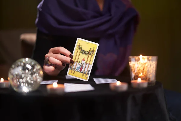 12.02.20. Moscow, Russia. Close-up of fortunetellers hands with tarot card at table with candles, magic ball — Stock Photo, Image