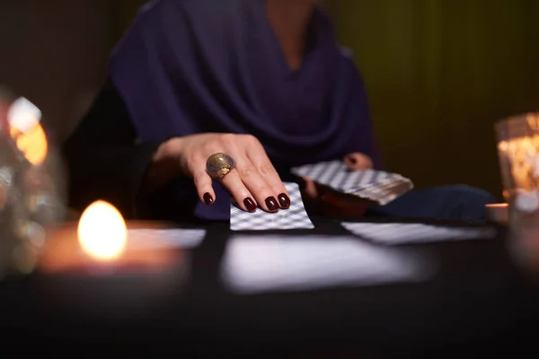 Primer plano de las manos de los lectores de mitones con tarjetas de adivinación en la mesa con velas — Foto de Stock