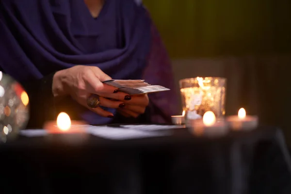 Nahaufnahme des Wahrsagers, der auf Karten tippt, die mit brennenden Kerzen am Tisch sitzen, magische Kugel — Stockfoto