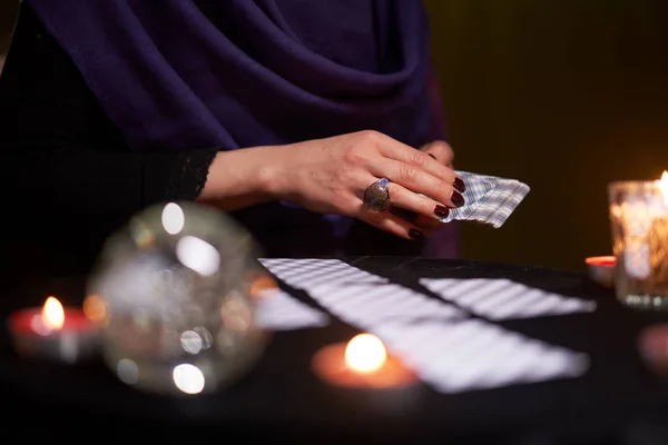 Cajero de la fortuna mujer en vestido púrpura divines en tarjetas sentadas a la mesa con velas —  Fotos de Stock