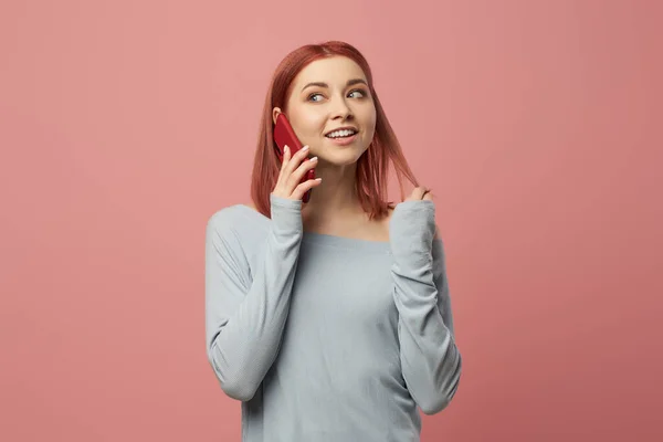 Ευτυχισμένη κοκκινομάλλα γυναίκα μιλάει στο τηλέφωνο, ενώ στέκεται στο στούντιο — Φωτογραφία Αρχείου