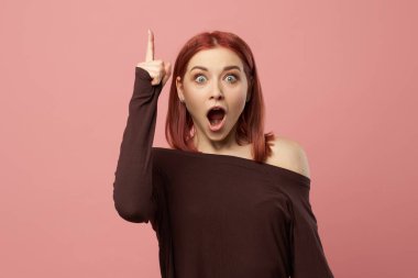 Elleri havada, gri gözlü, şaşkın kızıl bir kadın.