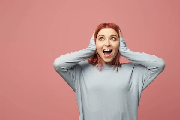 Glada ung kvinna täcker öronen med händer i studio — Stockfoto