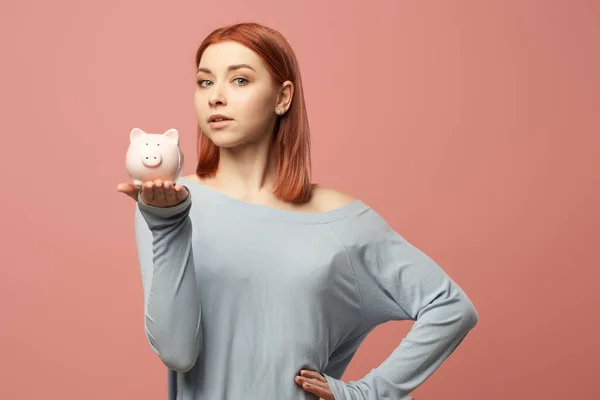 Jovem mulher com porquinho banco em mãos de pé no estúdio — Fotografia de Stock