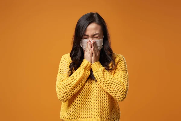Masked brunette woman sneezes while standing in studio — Stock Photo, Image