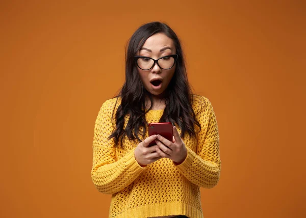 Surprised long-haired curly woman in glasses with phone in her hands — Stock Photo, Image