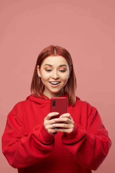Χαμογελαστή κοκκινομάλλα γυναίκα με το τηλέφωνο στα χέρια της στέκεται στο στούντιο — Φωτογραφία Αρχείου