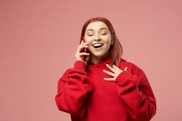 Mujer jengibre en suéter rojo hablando por teléfono aislado sobre fondo rosa — Foto de Stock