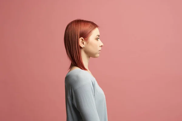 Дівчина-імбир у сірому светрі стоїть в студії ізольовано на рожевому фоні — стокове фото