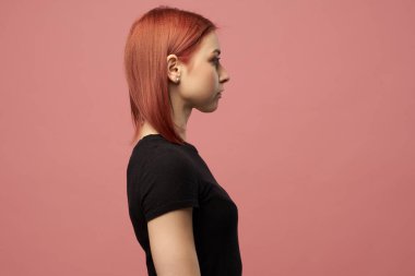 Siyah tişörtlü genç kızıl kadın pembe arka planda izole edilmiş.