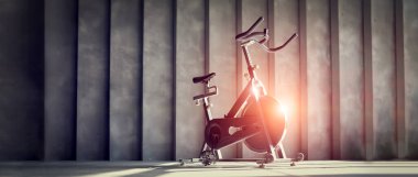 Spor salonundaki gri beton duvarda egzersiz bisikleti