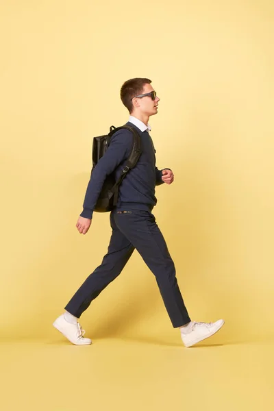 Young brunet man with backpack on isolated yellow background — Stock Photo, Image