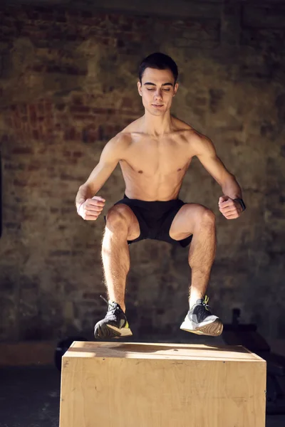 Springen sporter op houten doos in de sportschool — Stockfoto