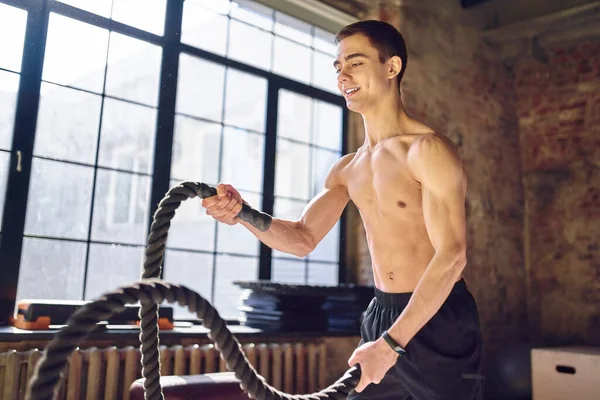 Spor salonunda kablolarla egzersiz yapan genç bir sporcu. — Stok fotoğraf
