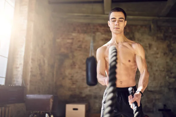 Sportsman with ropes against background of brick wall in gym — Stock Photo, Image