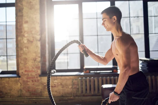 Jeune sportif faisant de l'exercice avec des câbles dans la salle de gym . — Photo