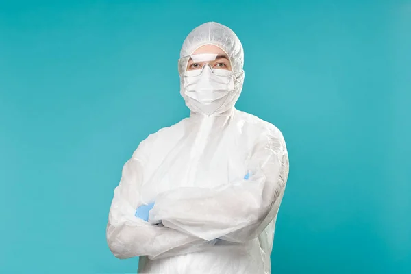 Hombre en traje protector, máscara médica, gafas con los brazos cruzados . — Foto de Stock