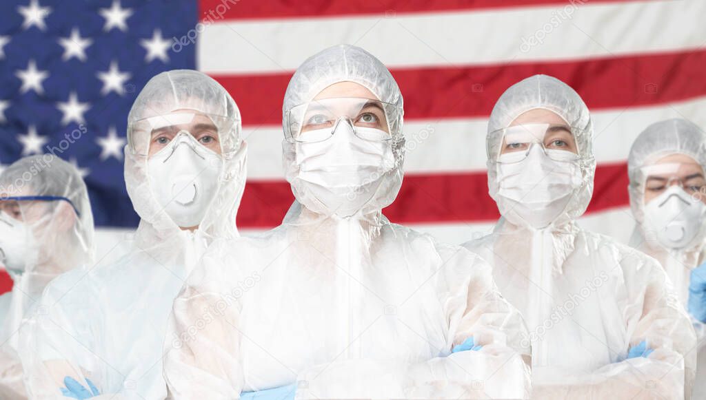 Portrait of doctors in protective suit at American flag. Coronavirus concept.