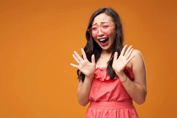 Schreeuwende aziatische vrouw in roze bril op lege oranje achtergrond — Stockfoto
