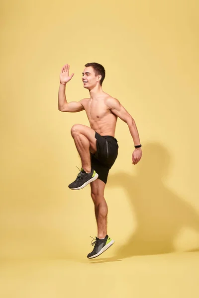 Seitenansicht eines jungen Sportlers, der im Studio läuft — Stockfoto