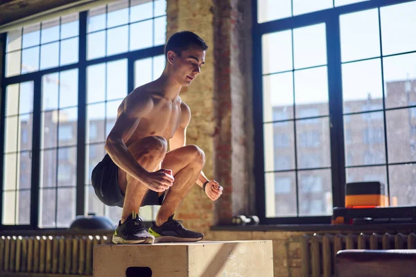 Zijaanzicht van springende jonge sporter op houten box in de sportschool — Stockfoto