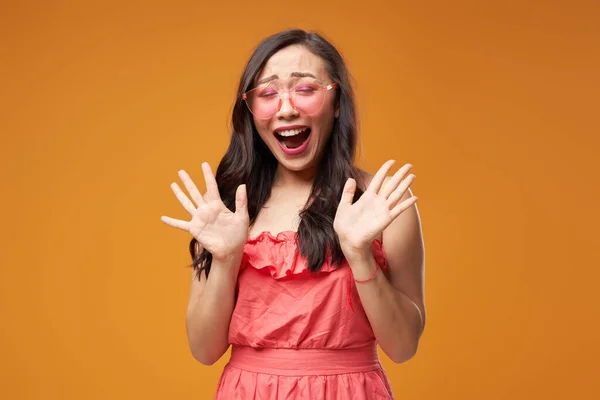 Gritando ásia menina no rosa óculos no vazio laranja fundo — Fotografia de Stock