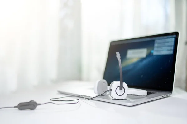 Laptop met zwart scherm, koptelefoon, microfoon op tafel op bokeh achtergrond. — Stockfoto