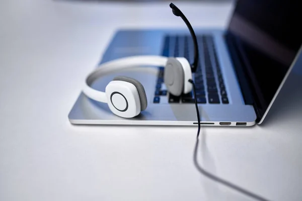Laptopkép, fehér fejhallgató mikrofonnal az asztalon. — Stock Fotó
