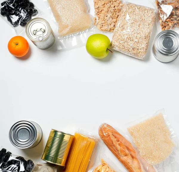 Verschiedene Lebensmittel in Plastiktüten, Dosen und Früchten auf weißem Hintergrund verpackt, Ansicht von oben. — Stockfoto