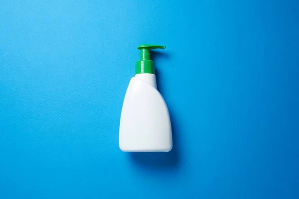 Soap bottle over blue background. Top view flat lay. — Stock Photo, Image