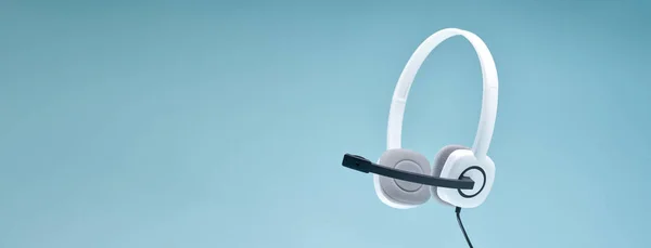 Auriculares con micrófono sobre fondo azul en blanco, lugar para texto . —  Fotos de Stock