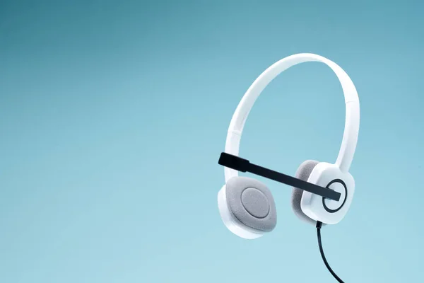 Auriculares blancos con micrófono aislado sobre fondo azul en blanco . — Foto de Stock