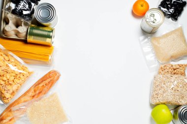 Beyaz arka planda plastik poşetlere, konservelere ve meyvelere kapatılmış çeşitli yiyecekler..