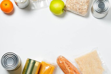 Beyaz arka planda plastik poşetlere, konservelere ve meyvelere kapatılmış çeşitli yiyecekler..