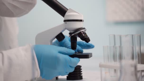 Γυναίκα επιστήμονας κοιτάζοντας μέσα από ένα μικροσκόπιο σε ένα εργαστήριο. — Αρχείο Βίντεο