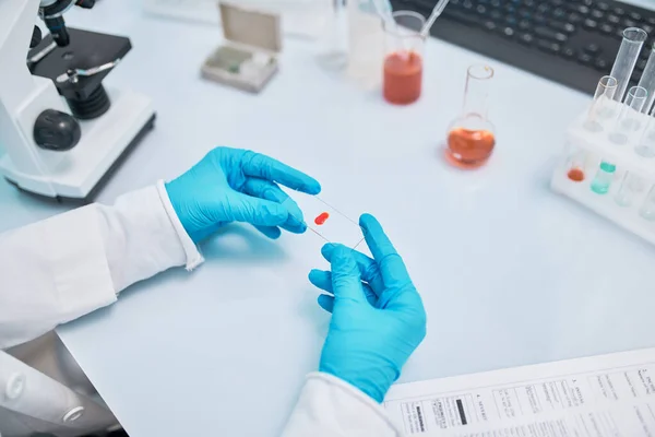 Asistente de laboratorio femenina sosteniendo diapositiva de vidrio con gota de sangre . — Foto de Stock