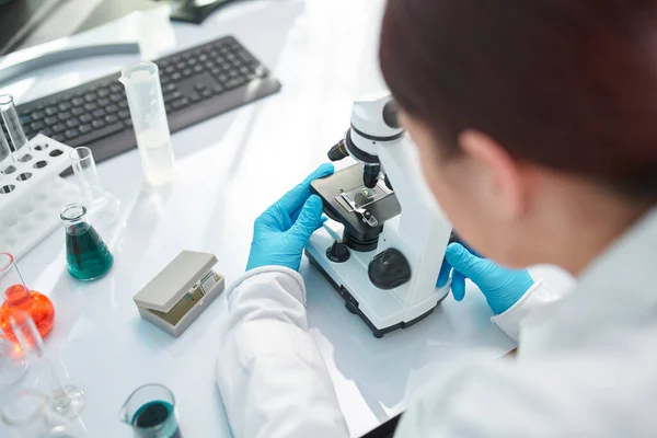 女性实验室助理在实验室显微镜下观察，特写镜头. — 图库照片