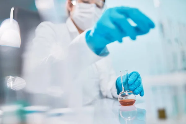 Woman lab technician with flask, blurred background. — Stock Photo, Image