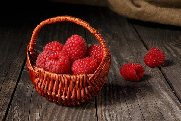 Raspberries in a basket on an old table — Stock Photo, Image