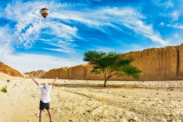 Turista olhando em balão voando sobre deserto — Fotografia de Stock