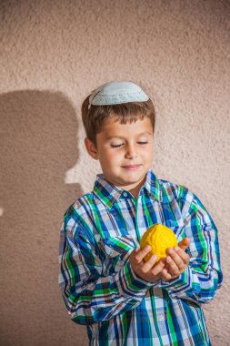boy in knitted kippah holding etrog  clipart