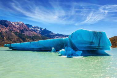 Huge white-blue iceberg floating in lake clipart