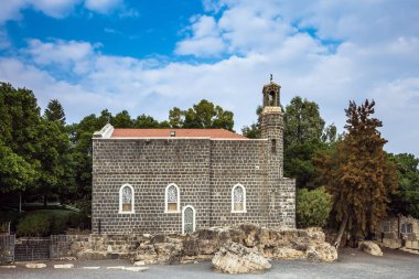 Yeşil ağaçların arkasında taşlarla kiliseyle