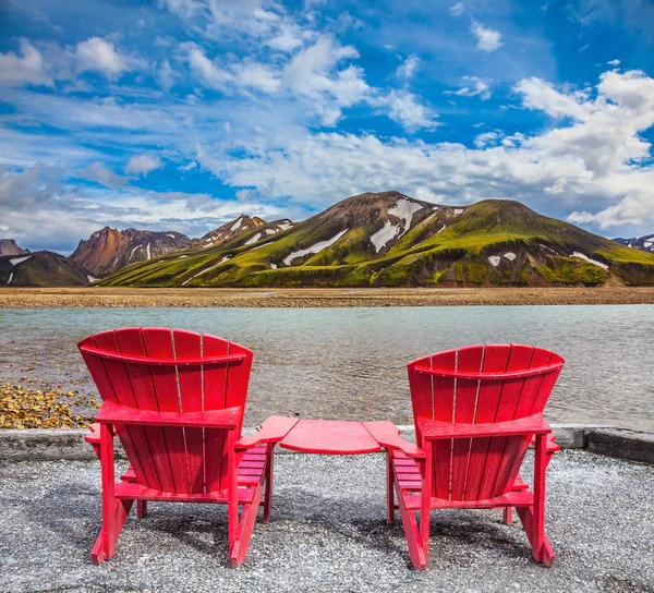 Rode ligstoelen onder de vallei in de buurt van stream — Stockfoto