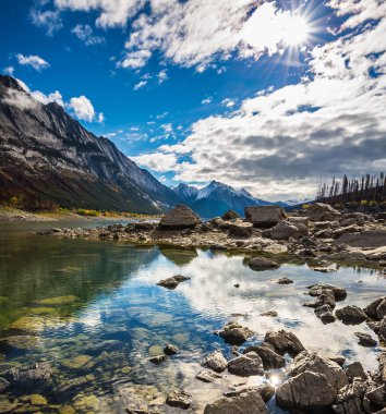 mavi gökyüzünün altında taşlarla shoaled saf Gölü